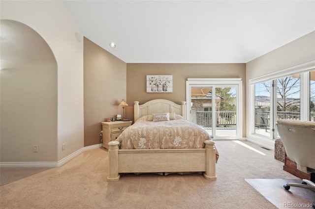 carpeted bedroom featuring baseboards, arched walkways, and access to exterior
