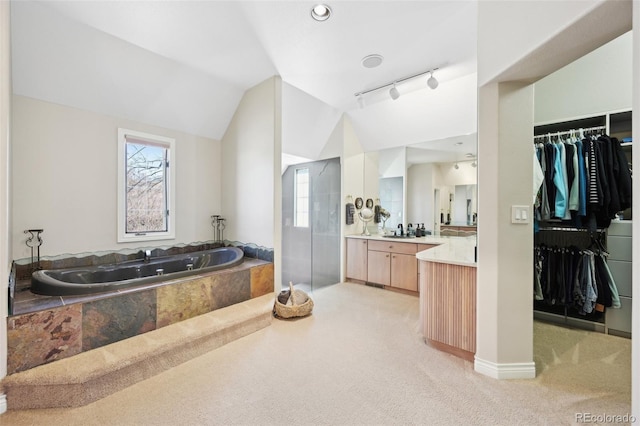 bathroom featuring vaulted ceiling, a healthy amount of sunlight, a garden tub, and vanity