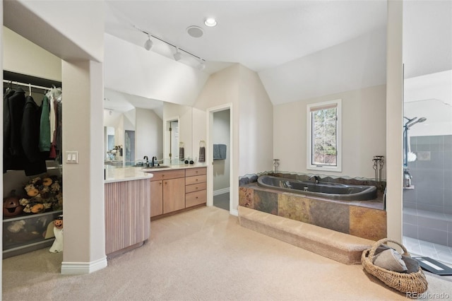 bathroom with track lighting, baseboards, vanity, and a bath