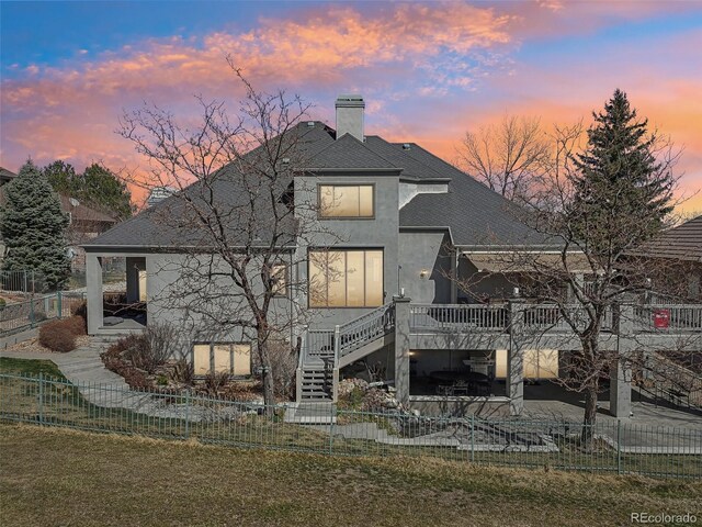 rear view of house with a deck, a chimney, a fenced backyard, and stairs