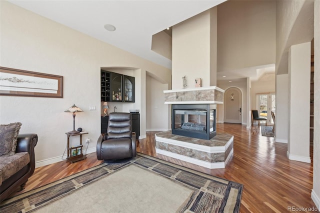 7081 Salvia St, Arvada, CO 80007 - living area with wood finished floors, a tiled fireplace, a high ceiling, and arched walkways