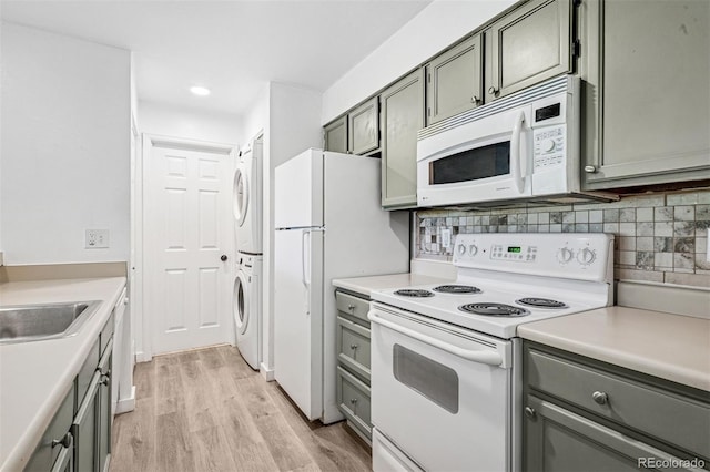 4899 S Dudley St Unit 7E, Littleton, CO 80123 - kitchen featuring white appliances, estacked washer and dryer, light wood finished floors, decorative backsplash, and light countertops