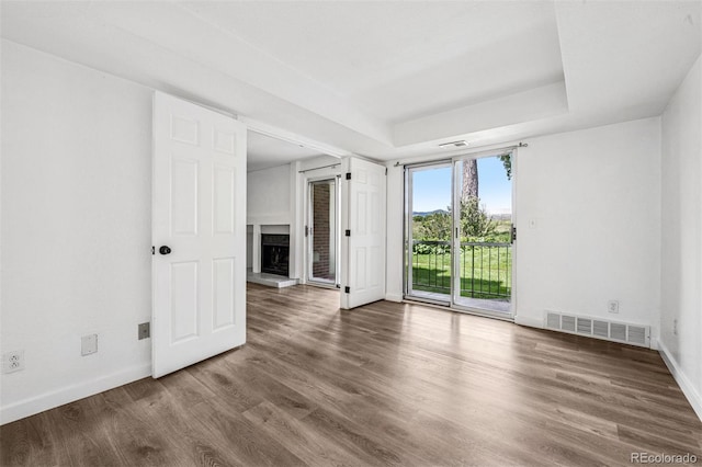 4899 S Dudley St Unit 7E, Littleton, CO 80123 - empty room featuring a fireplace with raised hearth, wood finished floors, and a raised ceiling