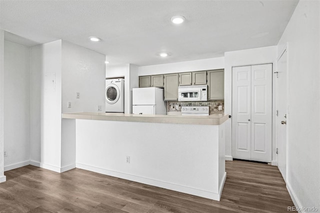 4899 S Dudley St Unit 7E, Littleton, CO 80123 - kitchen featuring white appliances, stacked washer and clothes dryer, dark wood-style flooring, light countertops, and tasteful backsplash