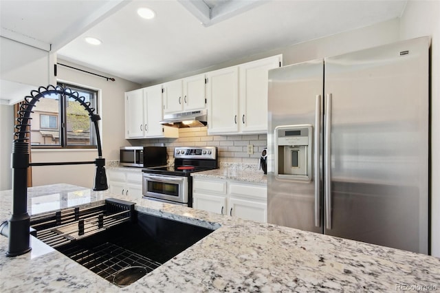 kitchen with under cabinet range hood, appliances with stainless steel finishes, light stone countertops, and white cabinets