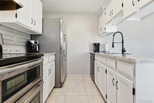 kitchen featuring a sink, black dishwasher, range with two ovens, under cabinet range hood, and tasteful backsplash
