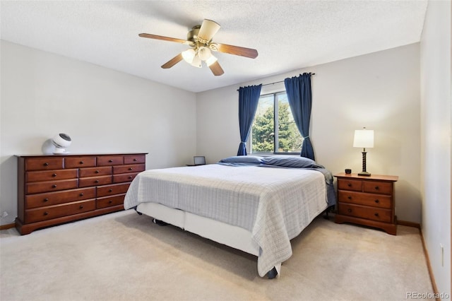 bedroom featuring light colored carpet, a textured ceiling, baseboards, and a ceiling fan