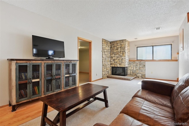 living area featuring a textured ceiling, visible vents, a fireplace, carpet flooring, and baseboards