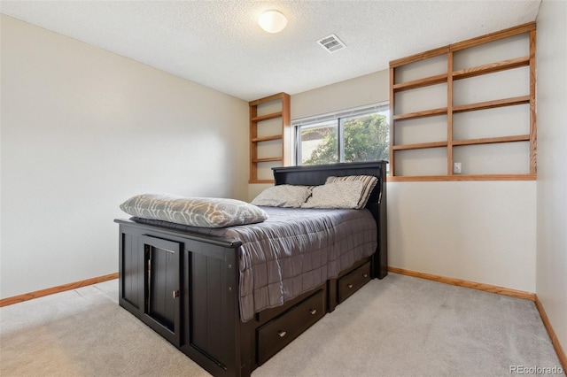 bedroom with light colored carpet, a textured ceiling, visible vents, and baseboards