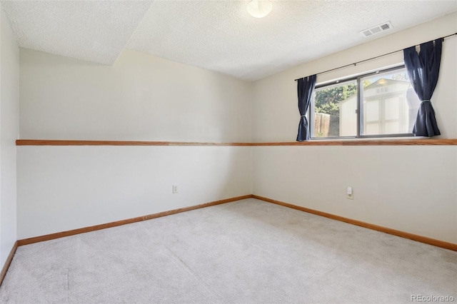spare room with baseboards, carpet flooring, visible vents, and a textured ceiling