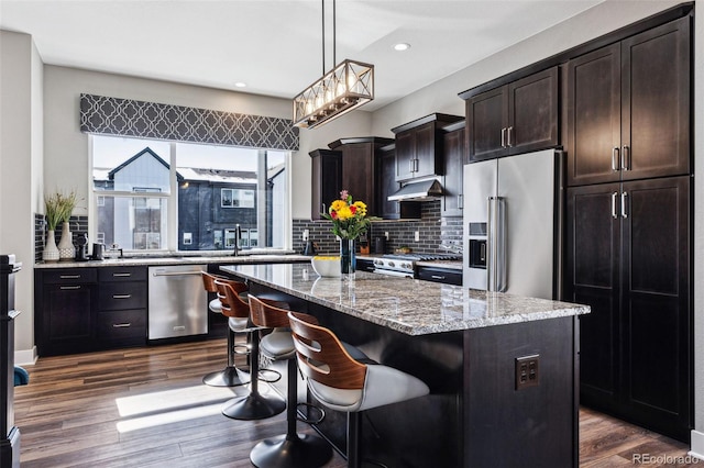 kitchen featuring dark brown cabinets, dark hardwood / wood-style floors, a kitchen island, and premium appliances