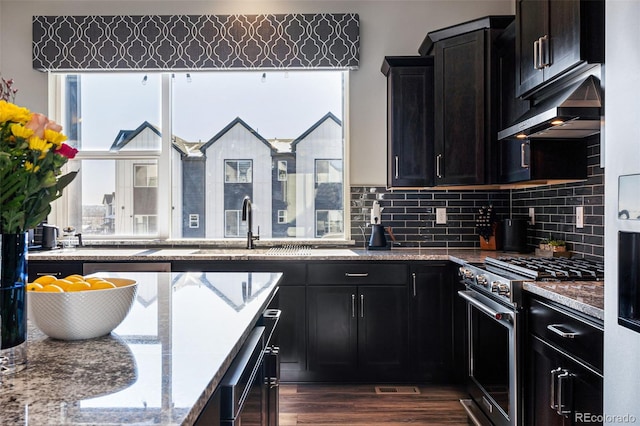 kitchen featuring backsplash, dark hardwood / wood-style floors, extractor fan, high end stainless steel range, and light stone countertops