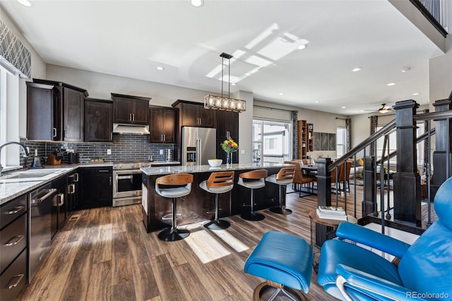 kitchen with sink, appliances with stainless steel finishes, dark hardwood / wood-style floors, a kitchen island, and pendant lighting