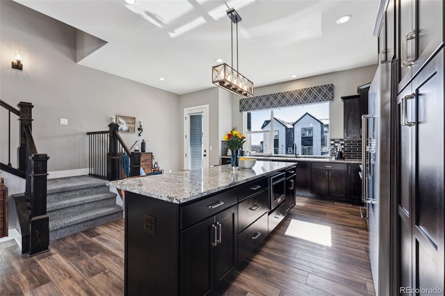 kitchen featuring dark hardwood / wood-style flooring, decorative light fixtures, a center island, and appliances with stainless steel finishes