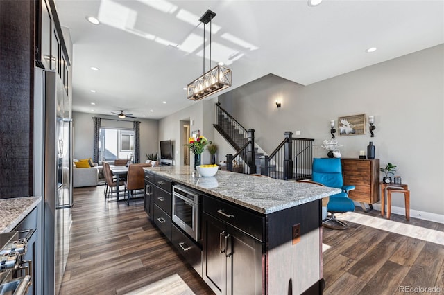 kitchen with pendant lighting, dark hardwood / wood-style floors, appliances with stainless steel finishes, and a kitchen island