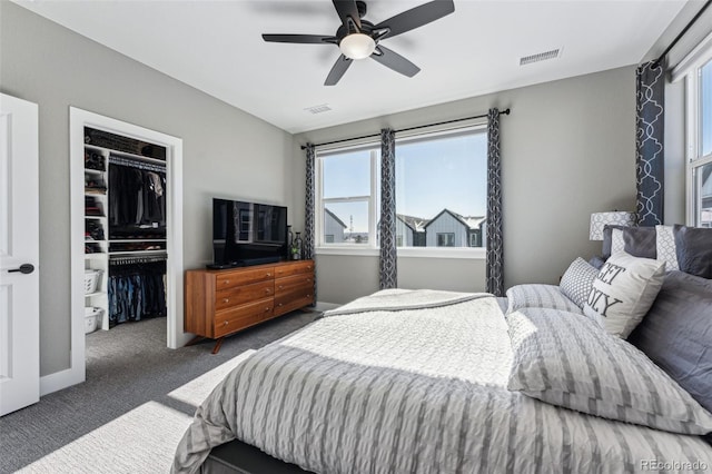 bedroom featuring multiple windows, ceiling fan, dark carpet, and a closet