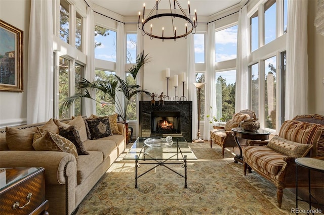 sunroom featuring a premium fireplace and a notable chandelier