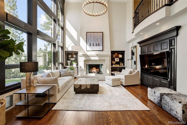 living room featuring a high ceiling, a chandelier, crown molding, and dark hardwood / wood-style flooring