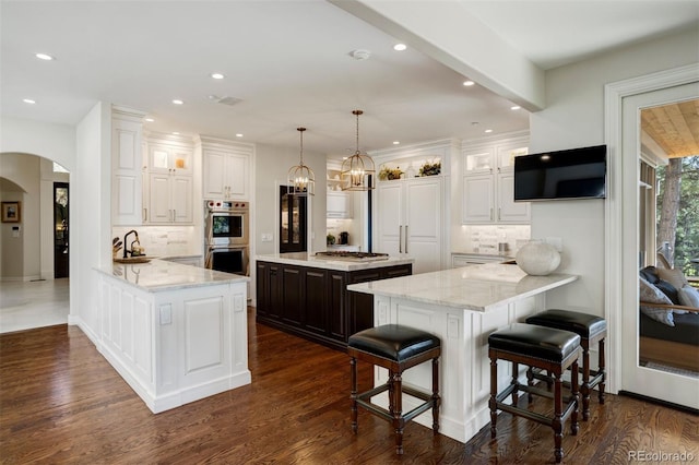 kitchen featuring stainless steel appliances, white cabinets, kitchen peninsula, and dark hardwood / wood-style flooring