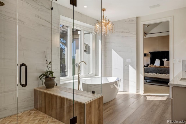 bathroom with an inviting chandelier, tile walls, hardwood / wood-style flooring, and separate shower and tub