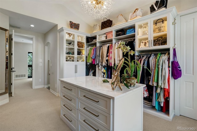 walk in closet featuring vaulted ceiling, an inviting chandelier, and light colored carpet