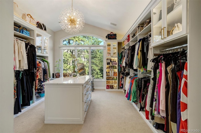 walk in closet with light colored carpet, a notable chandelier, and vaulted ceiling