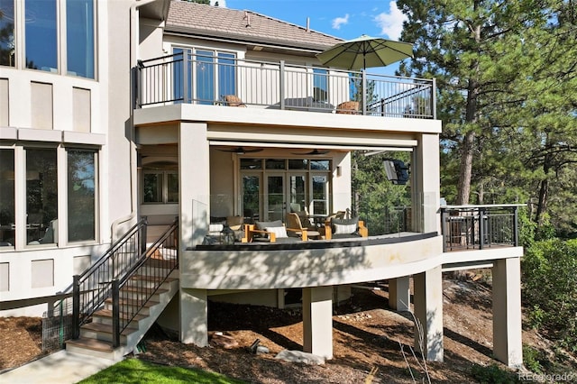 rear view of house featuring a balcony and an outdoor living space