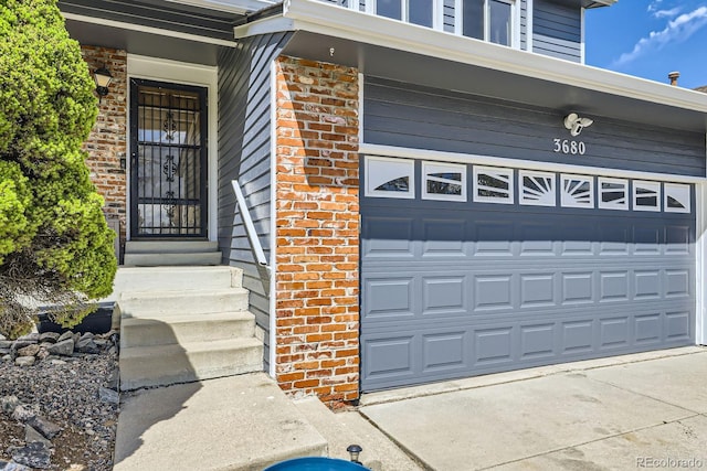 view of exterior entry featuring brick siding and an attached garage