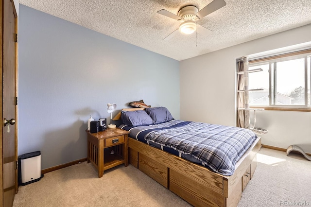 bedroom featuring light carpet, baseboards, a textured ceiling, and ceiling fan