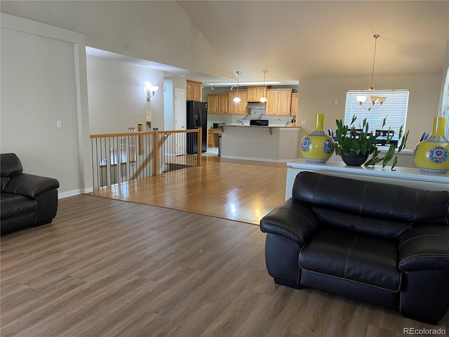 living room featuring hardwood / wood-style floors, high vaulted ceiling, and an inviting chandelier