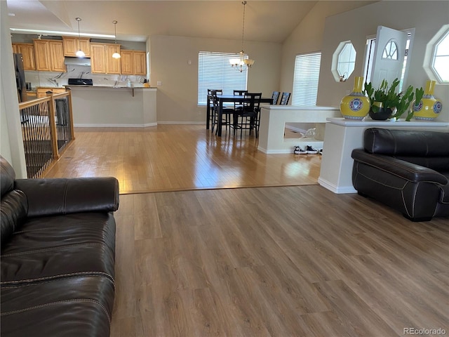 living room featuring an inviting chandelier, wood-type flooring, and vaulted ceiling