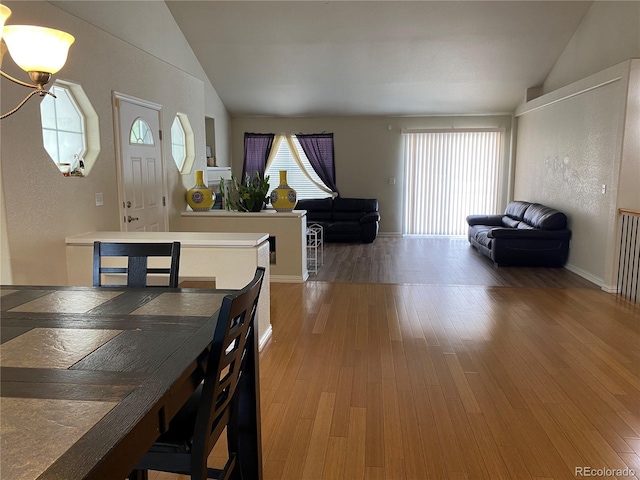 dining area with wood finished floors and vaulted ceiling