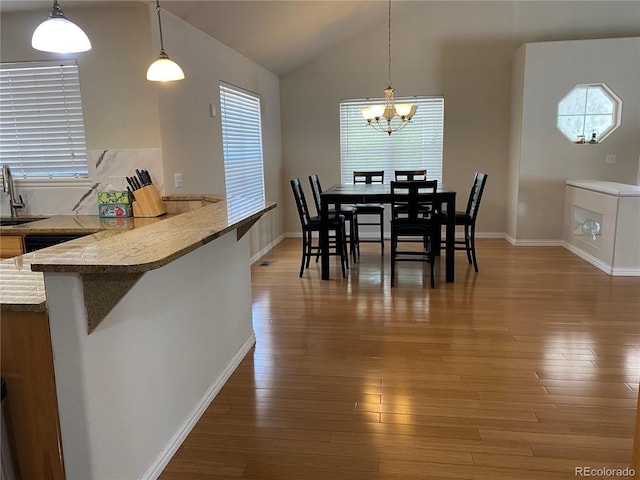 dining room featuring light wood finished floors, an inviting chandelier, baseboards, and vaulted ceiling