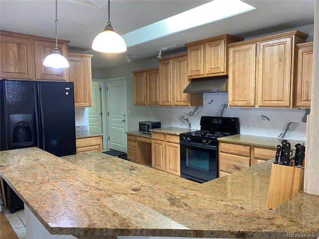 kitchen with hanging light fixtures, black appliances, light stone counters, and under cabinet range hood