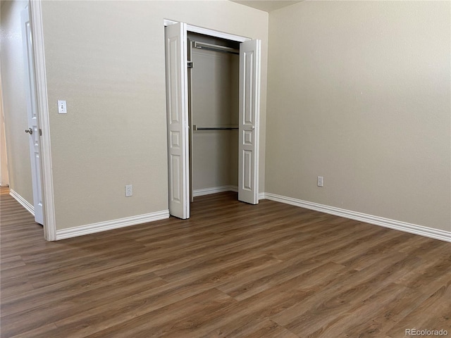 unfurnished bedroom featuring a closet, baseboards, and wood finished floors