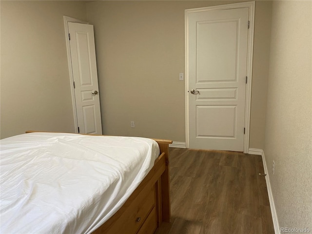 bedroom with dark wood-type flooring and baseboards