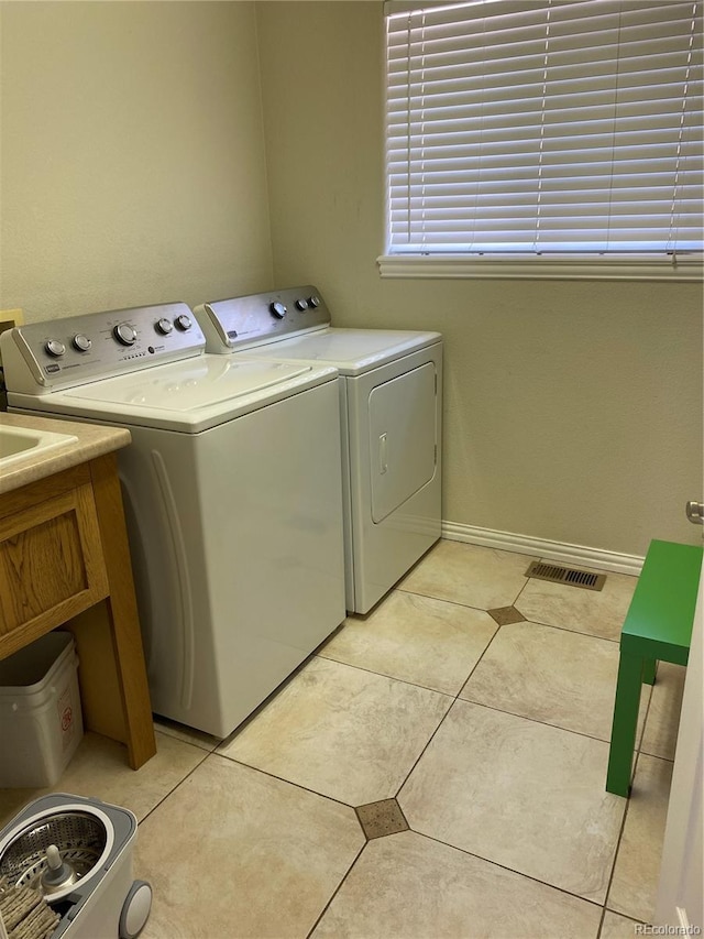 clothes washing area featuring separate washer and dryer, cabinets, and light tile patterned floors