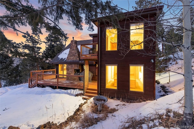 snow covered property featuring a wooden deck and a balcony