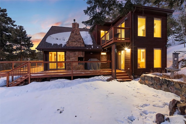 snow covered property featuring a wooden deck and a balcony