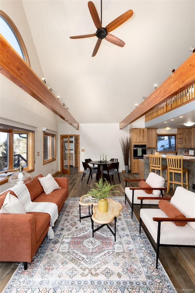 living room featuring beam ceiling, hardwood / wood-style flooring, ceiling fan, and a high ceiling