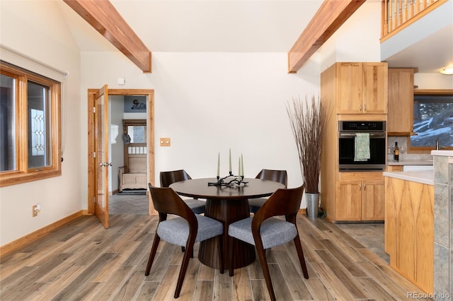 dining space featuring beamed ceiling, dark hardwood / wood-style flooring, and sink