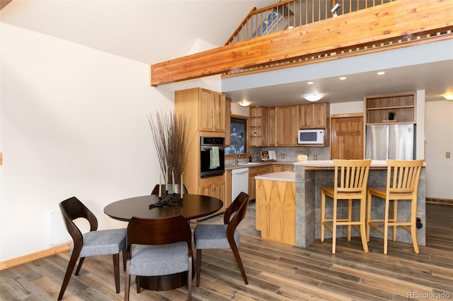 kitchen with wood-type flooring, sink, backsplash, and white appliances