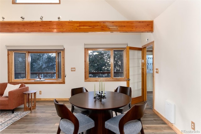 dining space with hardwood / wood-style flooring and lofted ceiling with beams