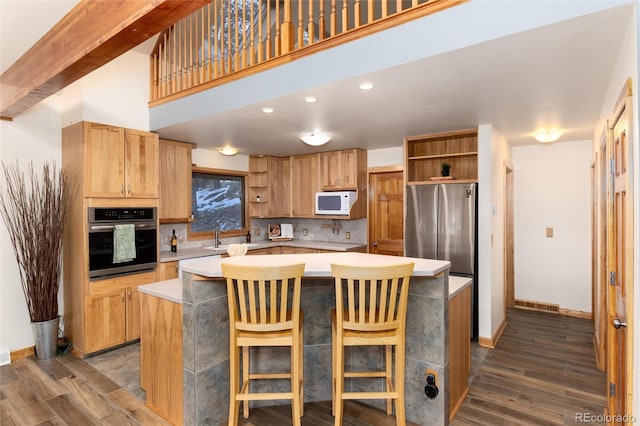 kitchen featuring a breakfast bar, appliances with stainless steel finishes, dark hardwood / wood-style flooring, and a center island