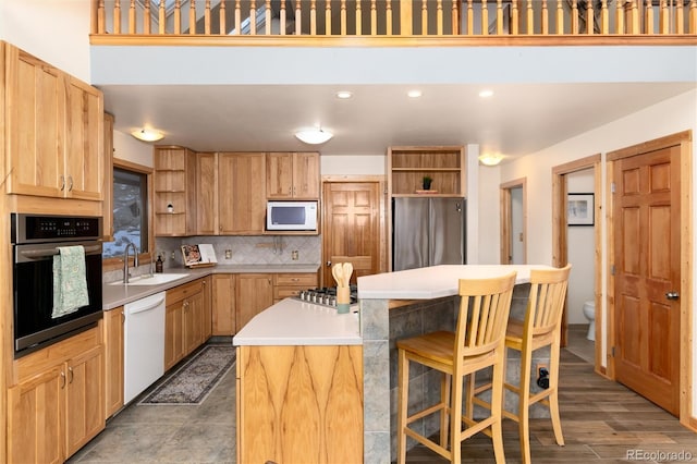 kitchen featuring a kitchen bar, sink, a center island, appliances with stainless steel finishes, and backsplash