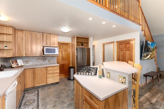 kitchen with sink, stainless steel appliances, a center island, tasteful backsplash, and light brown cabinets