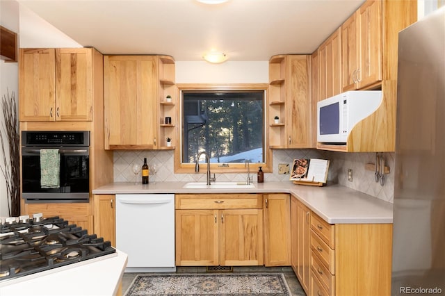 kitchen with appliances with stainless steel finishes, sink, and light brown cabinetry