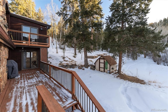 snow covered deck with a shed and grilling area