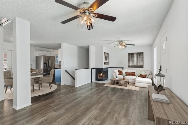 living room featuring ceiling fan, dark hardwood / wood-style floors, and a textured ceiling