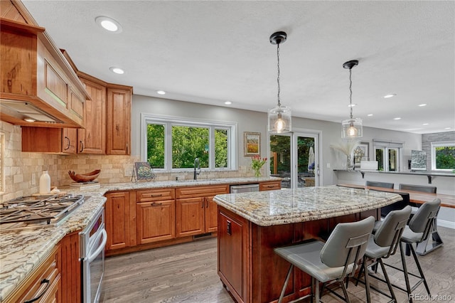 10289 E Berry Dr, Greenwood Village, CO 80111 - kitchen with light wood-style floors, a kitchen breakfast bar, a center island, backsplash, and recessed lighting